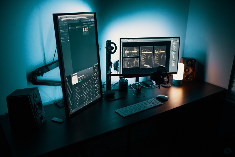 Desk in dark room with colorful screens